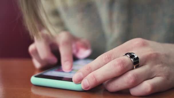 Primer plano de las manos femeninas escribiendo texto en un smartphone conectado a una red wifi en un café
. - Imágenes, Vídeo