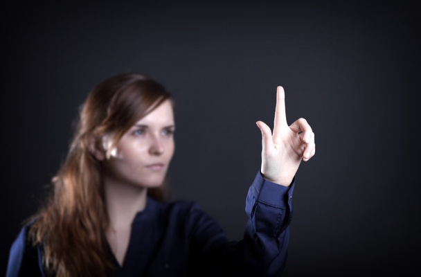 Woman with raised hand and one finger dark background - Photo, image