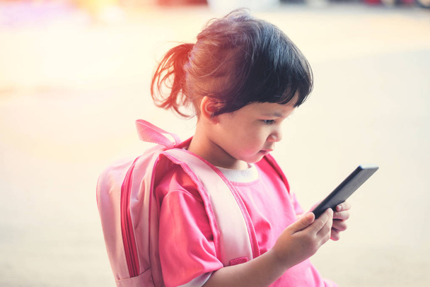 Діти грають смартфон / дитина дівчина утримання телефон в руках дивитися мультфільми в школі - Азії дитина 2-3 року старі діти пристрастився до проблем ігри за допомогою смартфона технології - Фото, зображення