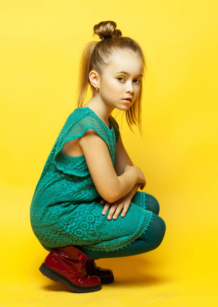 little fashion girl with blond hair posing over yellow background - Foto, Imagen