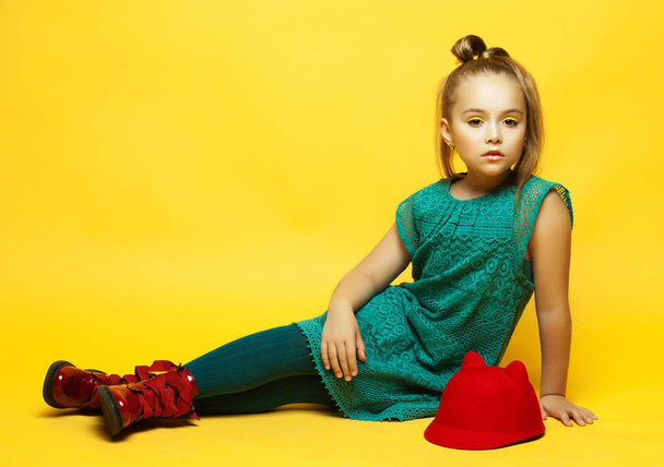 little fashion girl with blond hair posing over yellow background - Photo, image