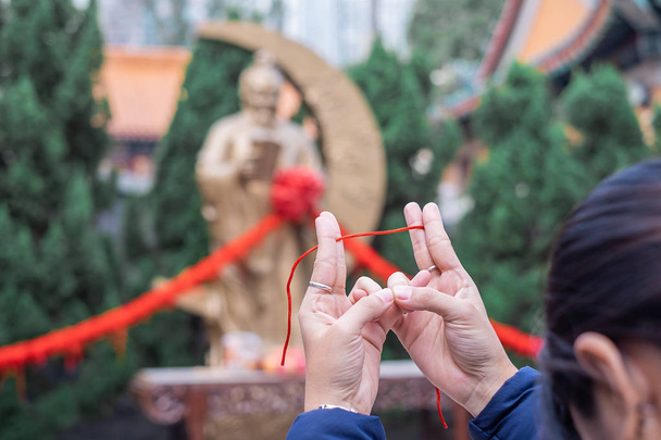 Νεαρή γυναίκα δεσμούς κόκκινο σχοινί και προσεύχονται σε Yue Λάος (ο Θεός του γάμου) στον ναό Wong Tai Sin, είναι καλά-γνωστός για την αγάπη και το γάμο προσευχές απαντηθεί. ορόσημο και διάσημες για τα τουριστικά αξιοθέατα του Χονγκ Κονγκ - Φωτογραφία, εικόνα