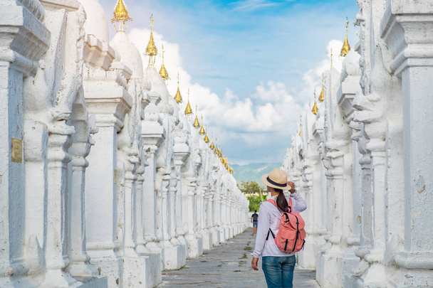 Ταξιδεύουν backpacker γυναίκα με καπέλο, ασιατικές ταξιδιώτης ψάχνει να λευκό παγόδα στον ναό Kuthodaw παγόδα είναι μια βουδιστική Στούπα, βρίσκεται στο Mandalay, Μυανμάρ, ορόσημο και δημοφιλή τουριστικά αξιοθέατα - Φωτογραφία, εικόνα