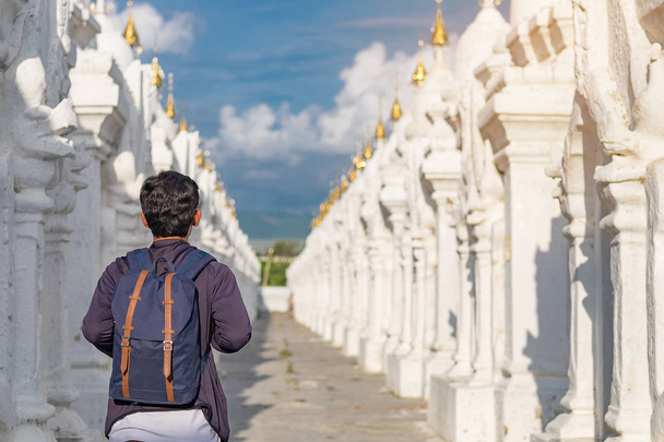 Hombre viajando con bolsa, viajero asiático que busca pagoda blanca en el templo de la pagoda Kuthodaw es una estupa budista, ubicada en Mandalay, Myanmar, punto de referencia y popular para las atracciones turísticas
 - Foto, Imagen