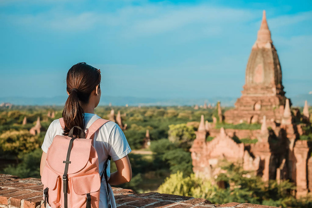 Jonge vrouw reizen backpacker met hoed, Aziatische reiziger staande op de pagode en op zoek naar mooie oude tempels, landmark en populaire voor toeristische attracties in Bagan, Myanmar. Azië reizen concept - Foto, afbeelding