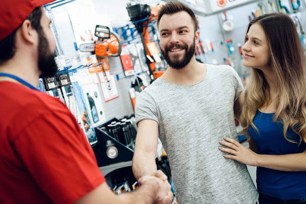 Salesman is shaking hands with bearded client in power tools store. - Foto, immagini