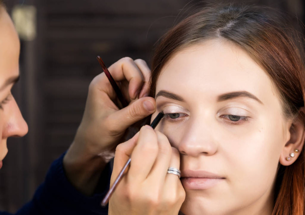 makeup artist preparing young beautiful woman. close-up eyeliner - Фото, зображення