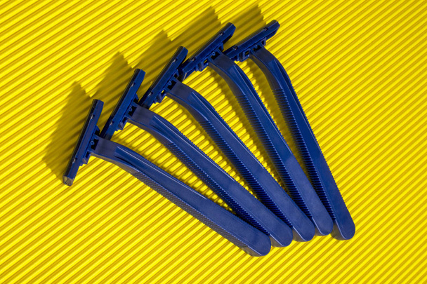 Cinco navajas desechables azules sobre un fondo amarillo
 - Foto, Imagen