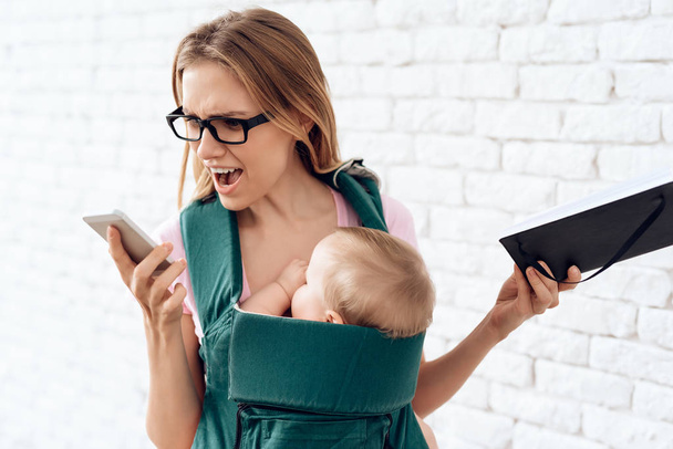 Agitated business woman talking phone with newborn. Business, motherhood concept. - Foto, afbeelding