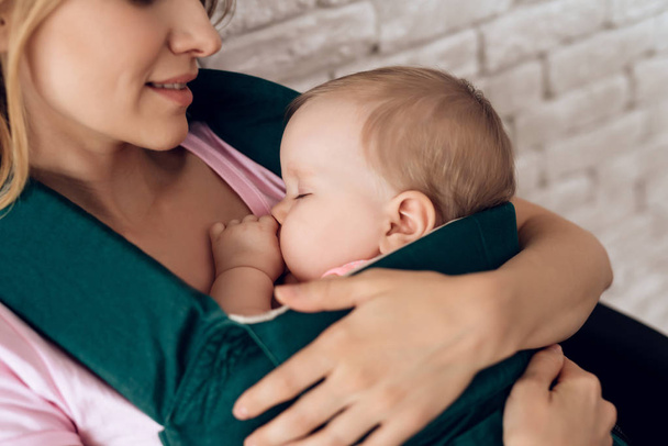 Young mother holding sleeping baby in baby sling. - Foto, Imagen