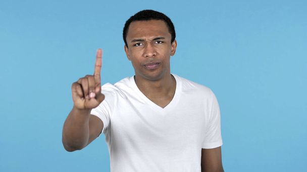 Afrikaner winkt mit dem Finger zur Weigerung isoliert auf blauem Hintergrund - Foto, Bild