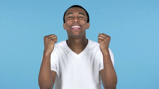 Happy Amazed Young African Man Surprised by Gift Isolated on Blue Background - Fotó, kép