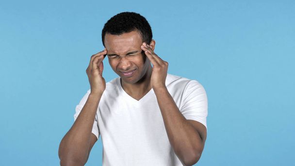 Jovem homem africano com dor de cabeça isolada em fundo azul - Foto, Imagem