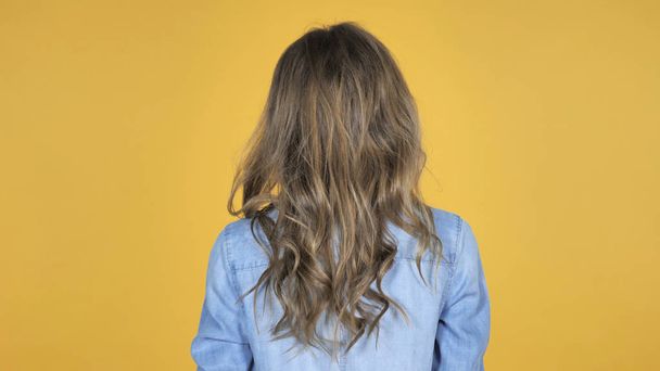 Back View of Young Girl Isolated on Yellow Background - Foto, afbeelding