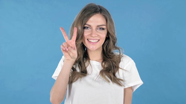 Victory Sign by Young Girl Isolated on Blue Background - Photo, Image