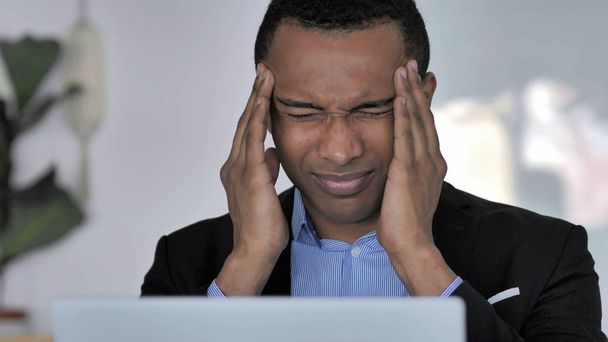 Primo piano di Stressed Casual uomo d'affari africano con mal di testa che lavora sul computer portatile
 - Foto, immagini