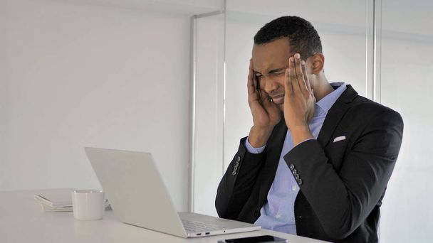 Mal de tête, stressé homme d'affaires africain travaillant sur ordinateur portable
 - Photo, image