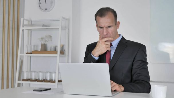 Pensive Middle Aged Businessman Thinking and Working on Laptop - Φωτογραφία, εικόνα