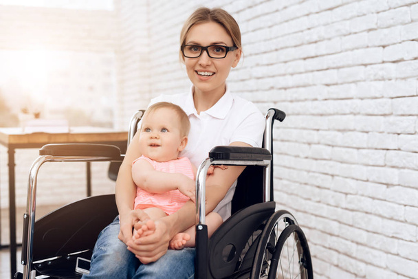 Smiling mother in wheelchair hugging newborn baby. - Fotografie, Obrázek