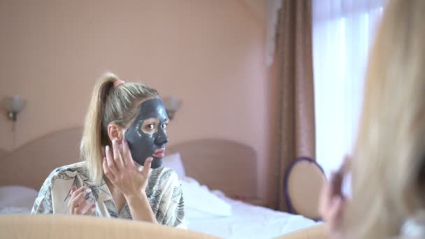 Una giovane donna gode di una maschera di argilla cosmetica
. - Filmati, video