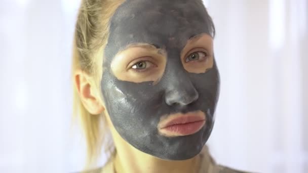 Portret van een jonge vrouw met een crème of cosmetische masker op de huid van het gezicht. - Video