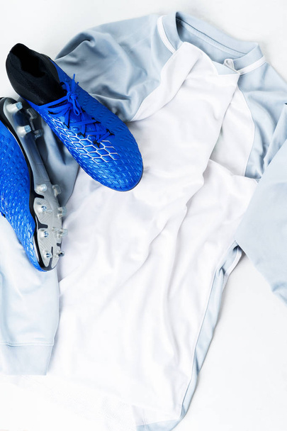 Close view of pair of football soccer boots cleats shoes on white t-shirt uniform - Fotó, kép
