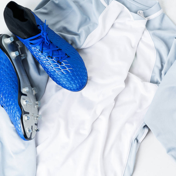 Close view of pair of football soccer boots cleats shoes on white t-shirt uniform - Photo, Image