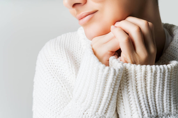 Cropped shot of female in white knitted woolen sweater with fingers near face. Emotional balance. - Fotó, kép