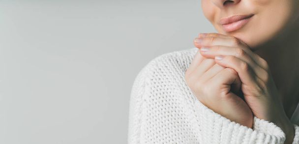 Cropped shot of female in white knitted woolen sweater with fingers near face. Emotional balance. - Foto, Imagem