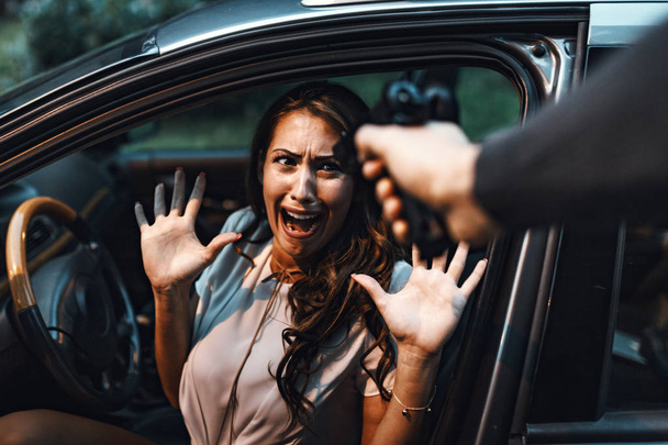 Опасный мужчина грабит женщину с пистолетом в машине
 - Фото, изображение