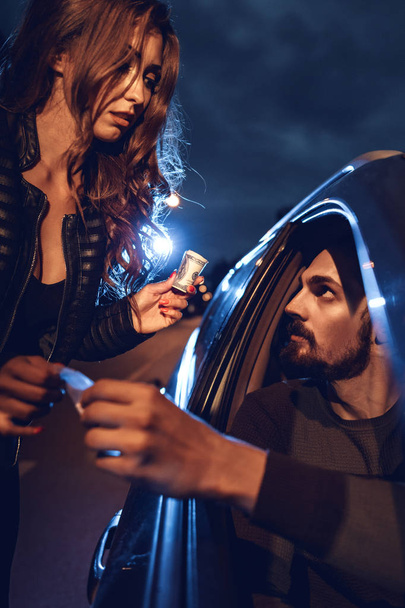 Close view of dealer selling little bag of drugs to young woman from car - Fotoğraf, Görsel