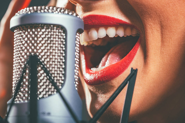 Zamknij widok kobiet otwarte usta z czerwona szminka śpiewu na mikrofon - Zdjęcie, obraz