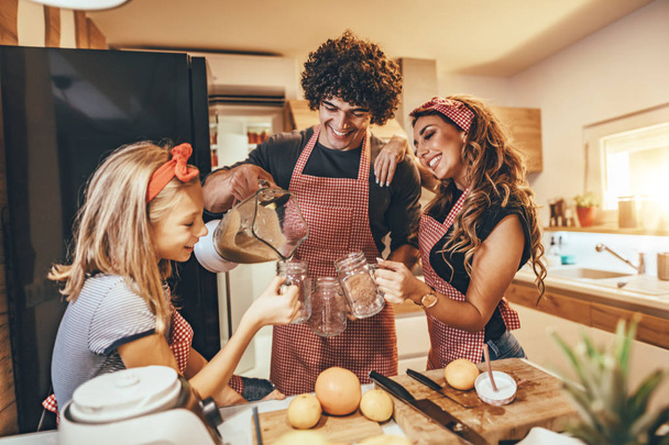 Happy parents with daughter preparing healthy meal in kitchen  - Photo, Image
