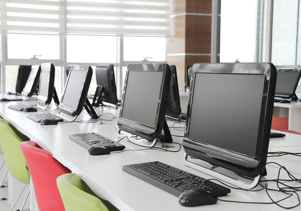 Sala de informática vazia com monitores e teclados seguidos para alunos e alunos em um laboratório de informática da escola
 - Foto, Imagem