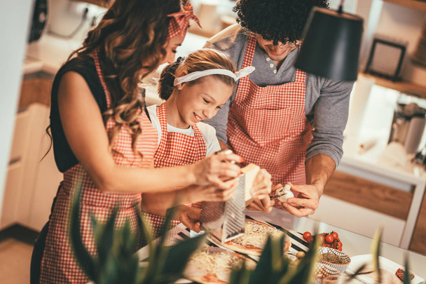 Happy parents and daughter preparing meal together in kitchen - Foto, Imagen