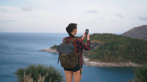 Podróżnik Kobieta, podziwiając widok na morze i Dokonywanie zdjęcie na plaży przy użyciu smartfona - Zdjęcie, obraz