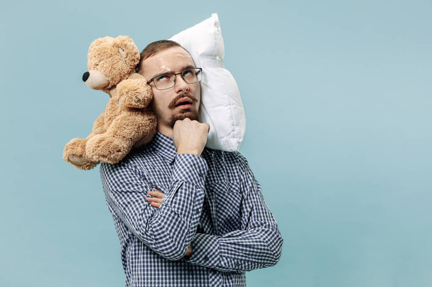 Hombre cansado durmiendo en casa con demasiado trabajo. Empresario aburrido con almohada y oso de juguete
 - Foto, Imagen