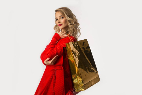 beautiful young girl in a red dress with packages in their hands on a white background - Foto, afbeelding
