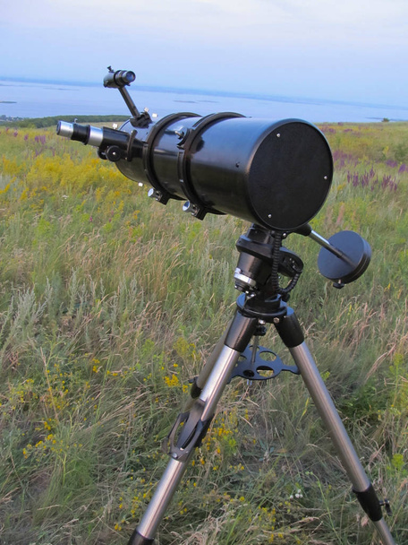 Een telescoop staat in de weide in de schemering - Foto, afbeelding
