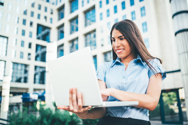 happy young businesswoman working on laptop on background of business center - Photo, Image