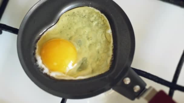 Cooking a fried egg in a mini pan in the shape of a heart for Valentine's Day. Slow motion shot - Footage, Video
