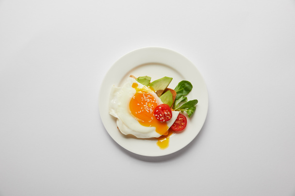 vista superior del huevo revuelto con tomate cherry y aguacate en plato sobre fondo gris
 - Foto, imagen
