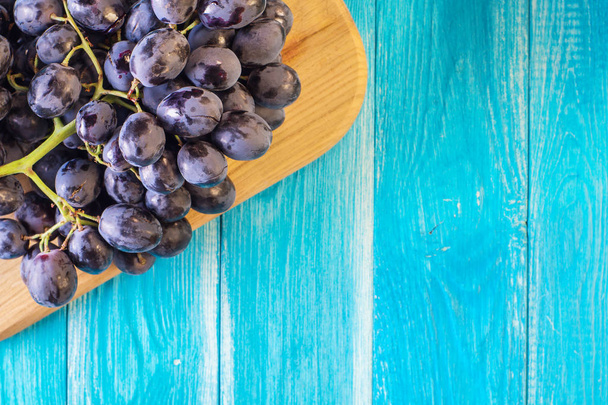 Uvas em uma mesa de madeira azul. Ramo de uvas vermelhas maduras frescas. Belo fundo com um ramo de uvas azuis. Uvas de vinho tinto escuro. Fundo Alimentar Saudável. Frutos de verão
. - Foto, Imagem
