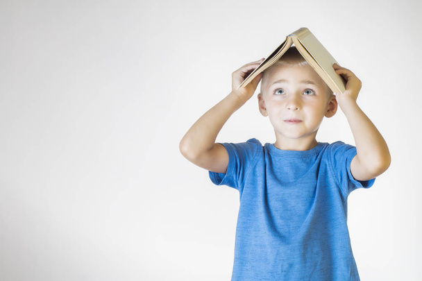 Портрет маленького улыбающегося школьника с книгой. Веселый улыбающийся малыш. Школа
. - Фото, изображение