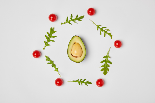 top view of avocado, arugulas leaves and cherry tomatoes on grey background - Foto, immagini
