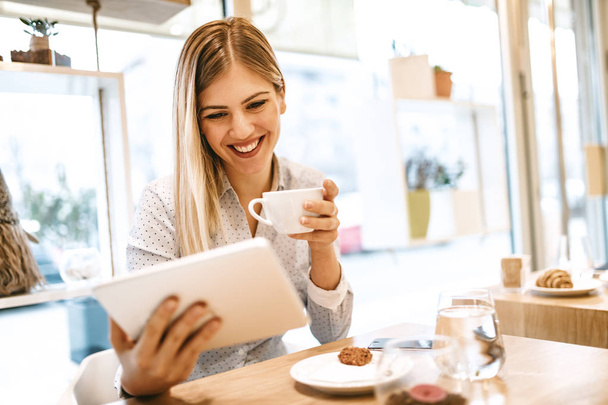 junge lächelnde Geschäftsfrau in Kaffeepause im Café mit Tablet-Computer  - Foto, Bild