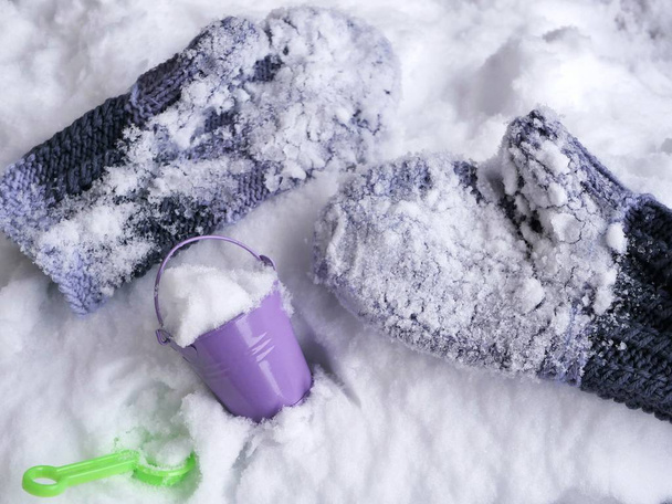Woolen mittens in the snow, a toy bucket and a shovel on the snow, seasonal winter holidays - Photo, Image