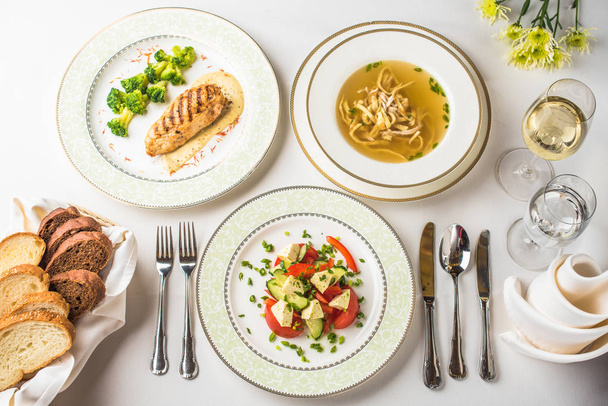δείπνο στο εστιατόριο με σούπα, σαλάτα και κύρια κατάρα σερβίρεται σε λευκό τραπέζι - Φωτογραφία, εικόνα