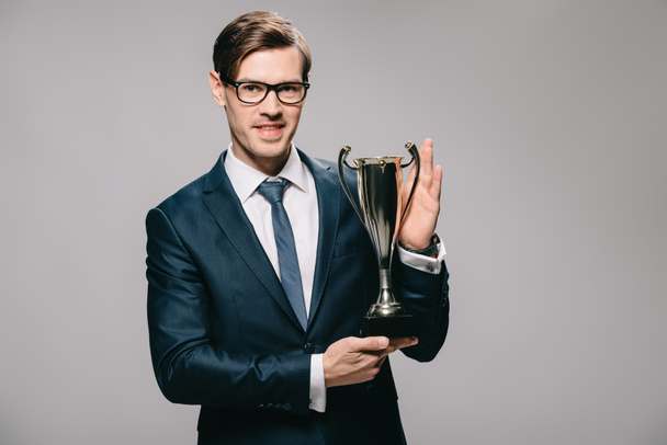 bonito empresário segurando troféu em mãos isoladas em cinza
 - Foto, Imagem