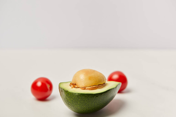 selektiver Fokus von geschnittenen Avocados und Kirschtomaten auf grauem Hintergrund - Foto, Bild